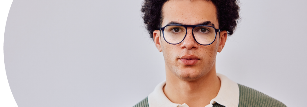 Junger Mann trägt eine Brille und blickt direkt in die Kamera